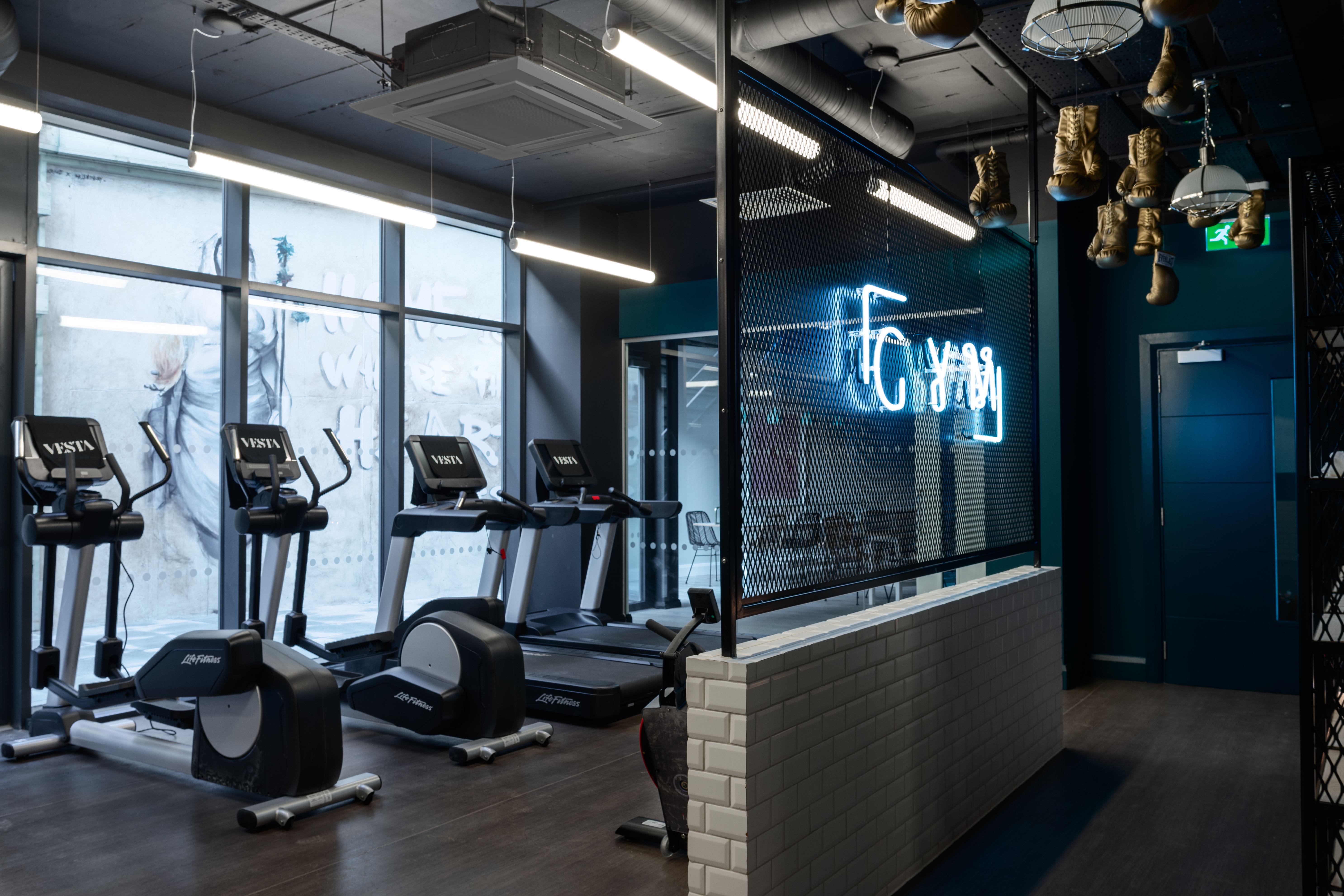 Industrial-style gym with neon signage and boxing area
