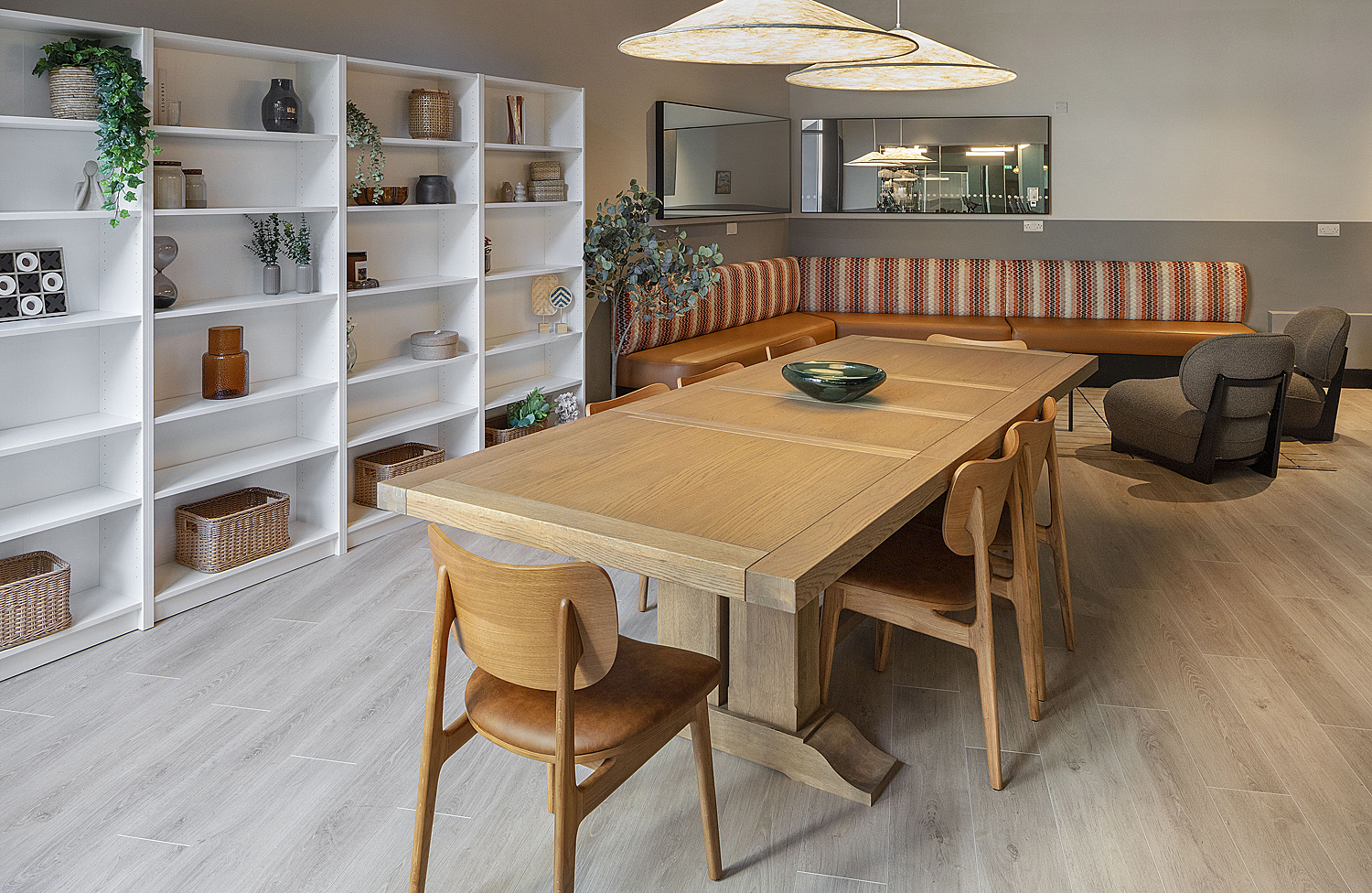 Communal dining table beside open shelving and banquette seating